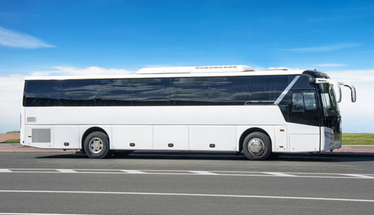 a plain white charter bus parked in a lot